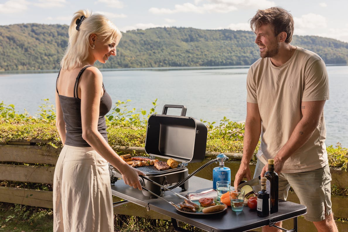 Svart hopfällbart campingbord med stålram som grillstation vid sjö