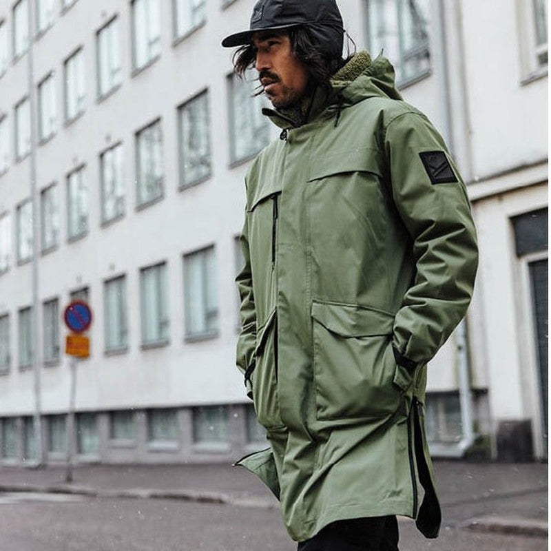 Grön Halti parka för män med stor huva och armficka, stadsmiljö
