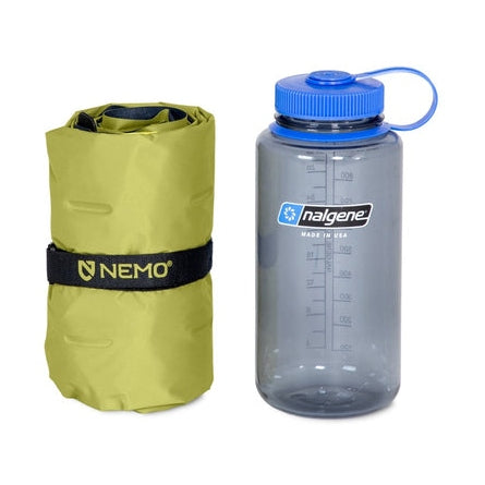 Rullat limegrönt NEMO Eclipse liggunderlag bredvid Nalgene-flaska för packvolym