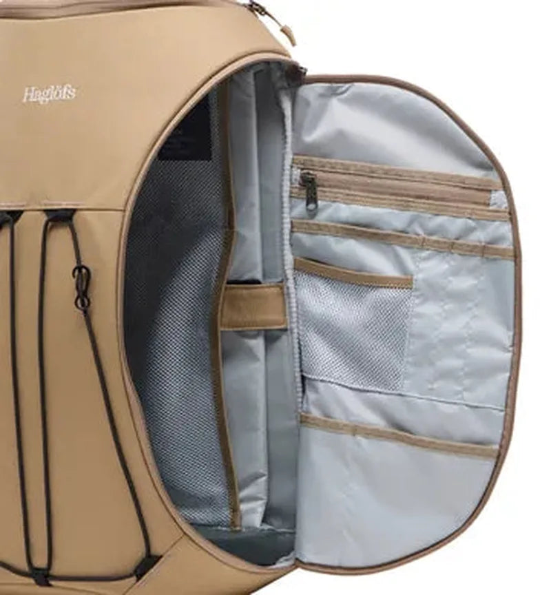 Inre organisering beige ryggsäck med gråa fickor, mesh-fack och Haglöfs-logotyp
