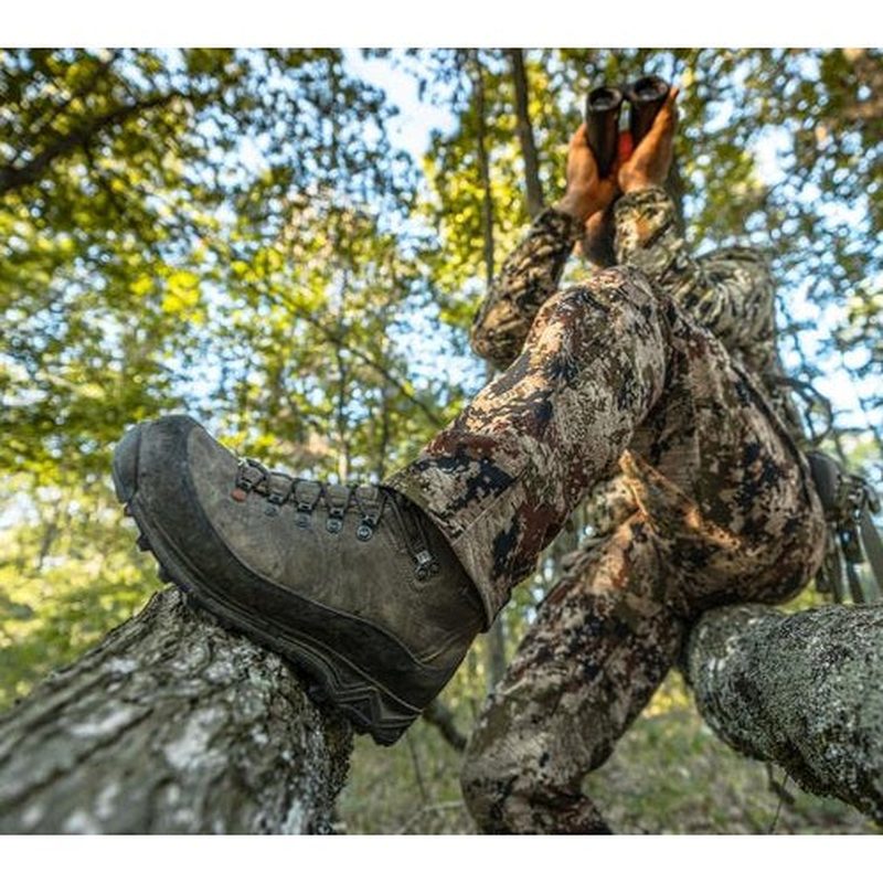Jägare med kikare och bruna vandringsskor i skog