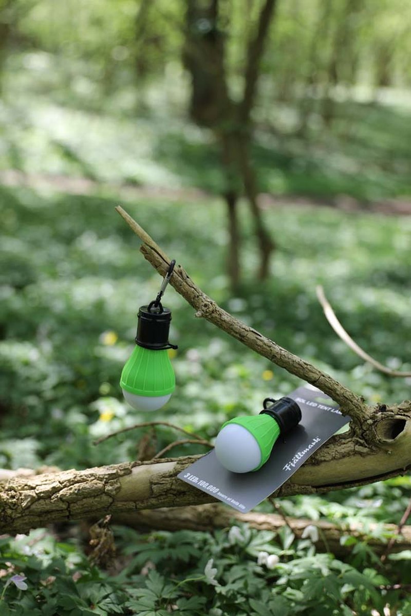 Grön vit Sol LED tältlampa med karbinhake hängande i skog