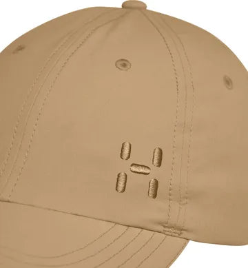 Närbild på beige Haglöfs keps som visar tygdetaljer och H-logo