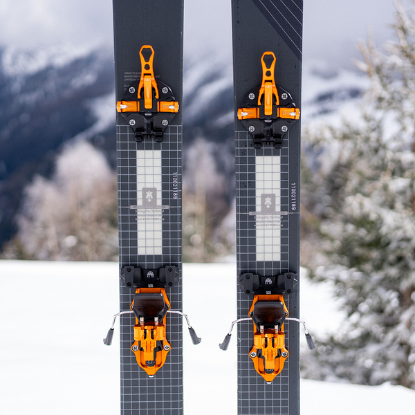 Orange ATK Freerider 15 EVO bindningar monterade på mörkgråa skidor i snö