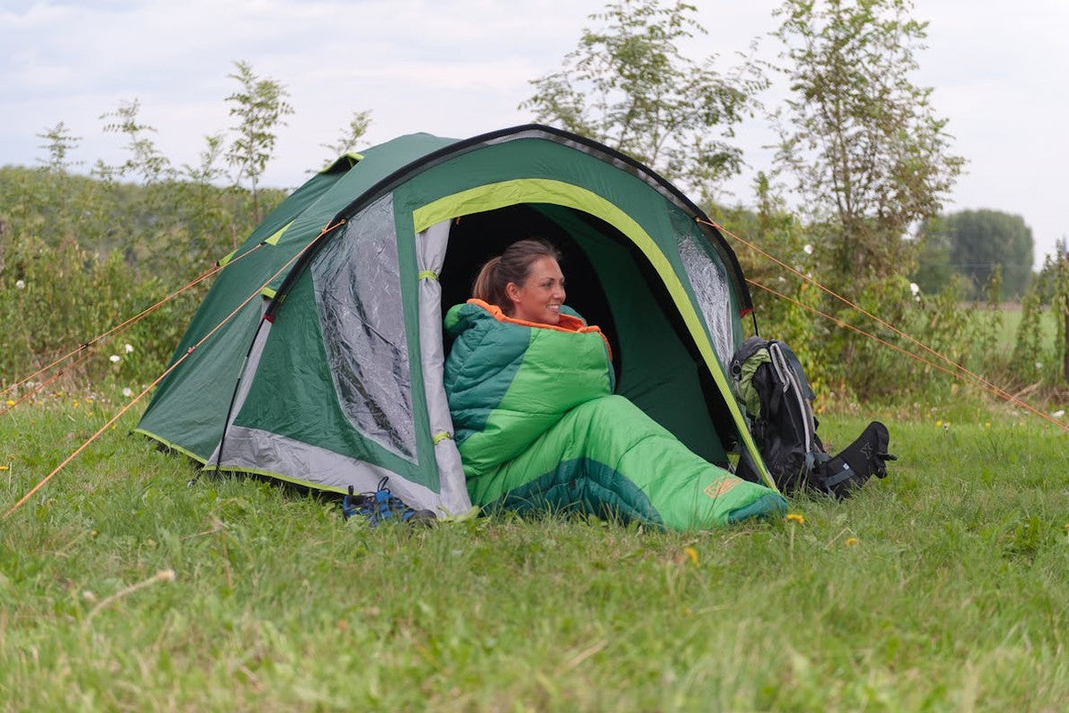 Campingtält med orange rep och ryggsäck på gräs