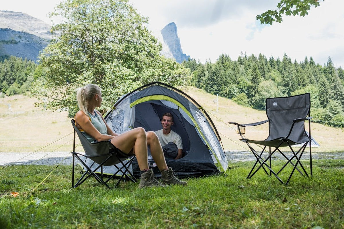 Grön hopfällbar campingstol med armstöd utomhus vid tält