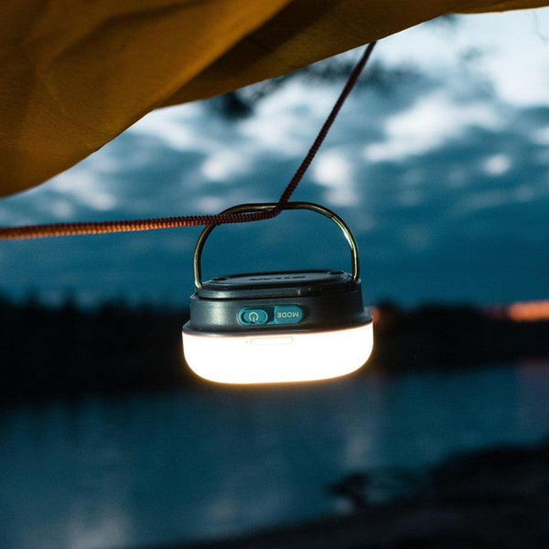 Varmt lägereldsken från campinglykta vid vatten