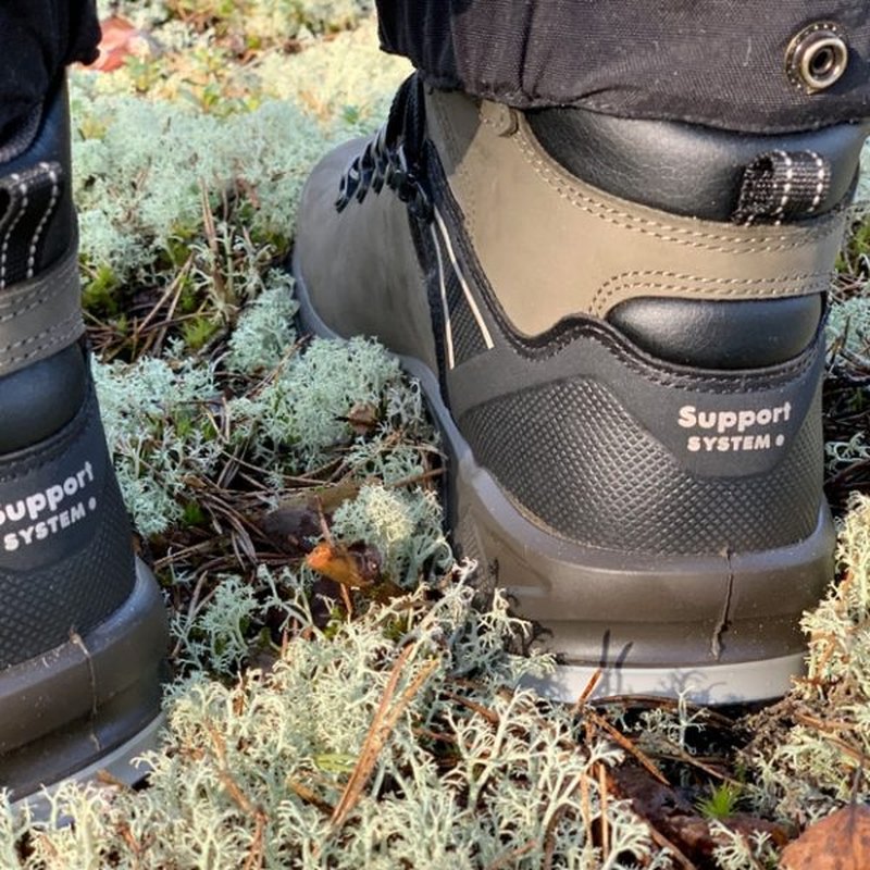 Hälsupportsystem på grön vandringskänga i lav