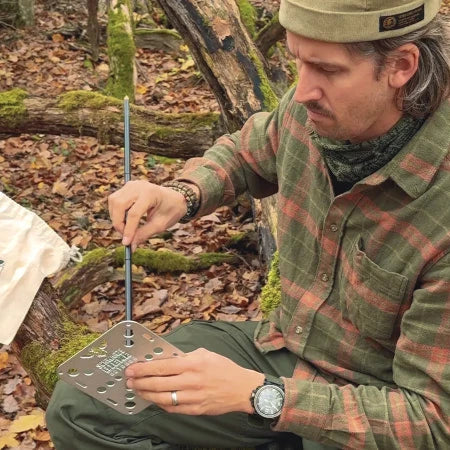 Man monterar silverfärgat Shorty campingbord i skogen
